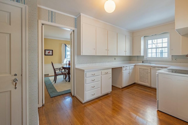 kitchen with range, light hardwood / wood-style floors, white cabinets, ornamental molding, and sink