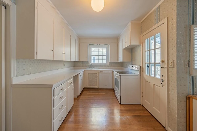 kitchen featuring sink, white cabinets, white appliances, ornamental molding, and light hardwood / wood-style flooring