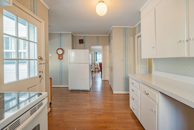 kitchen with white refrigerator, ornamental molding, light hardwood / wood-style floors, and white cabinetry