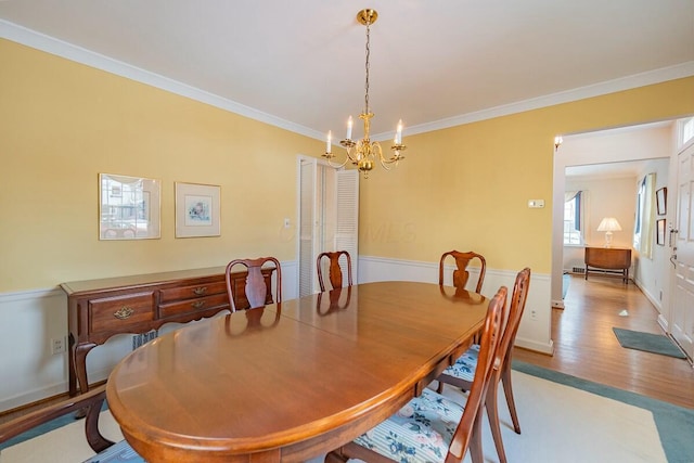 dining room with ornamental molding, light hardwood / wood-style flooring, and a notable chandelier