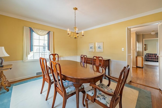 dining area featuring hardwood / wood-style floors, an inviting chandelier, and ornamental molding