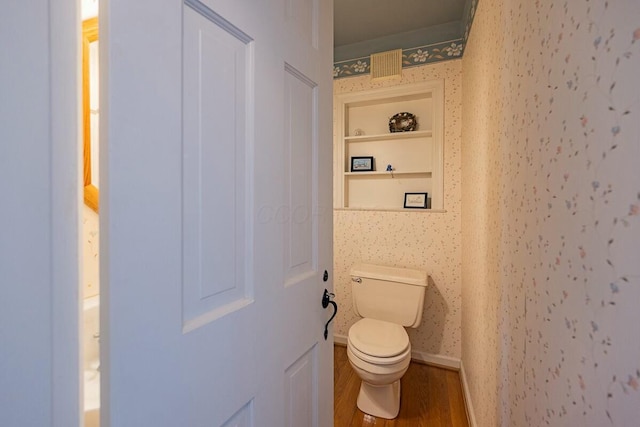 bathroom with toilet, built in shelves, and wood-type flooring