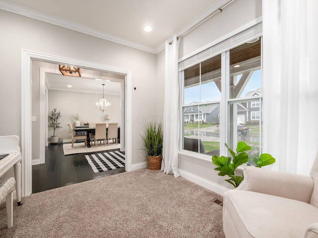 sitting room featuring dark carpet, crown molding, and a notable chandelier