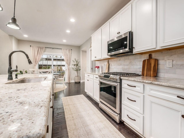 kitchen featuring pendant lighting, light stone counters, sink, and stainless steel appliances