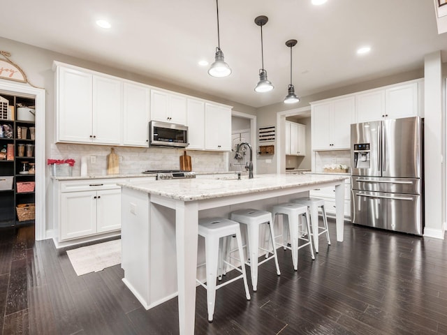 kitchen featuring a center island with sink, white cabinetry, and stainless steel appliances