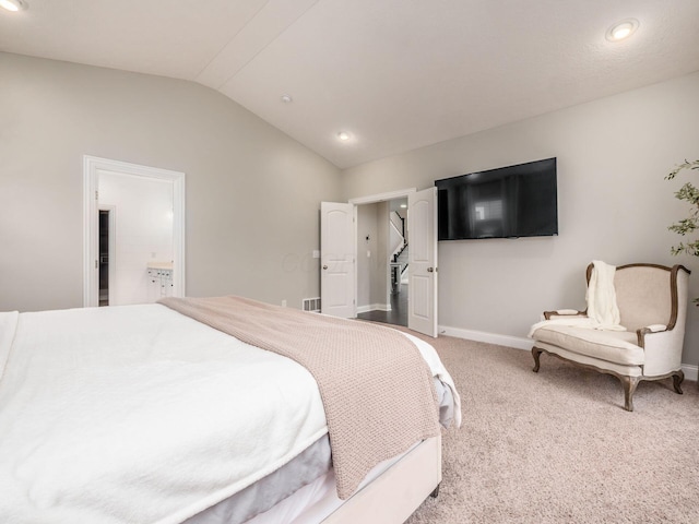 carpeted bedroom with ensuite bath and lofted ceiling