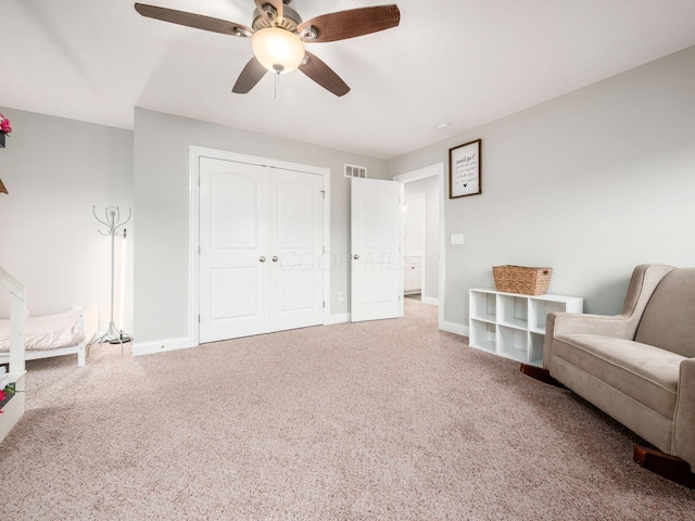 living area featuring carpet and ceiling fan