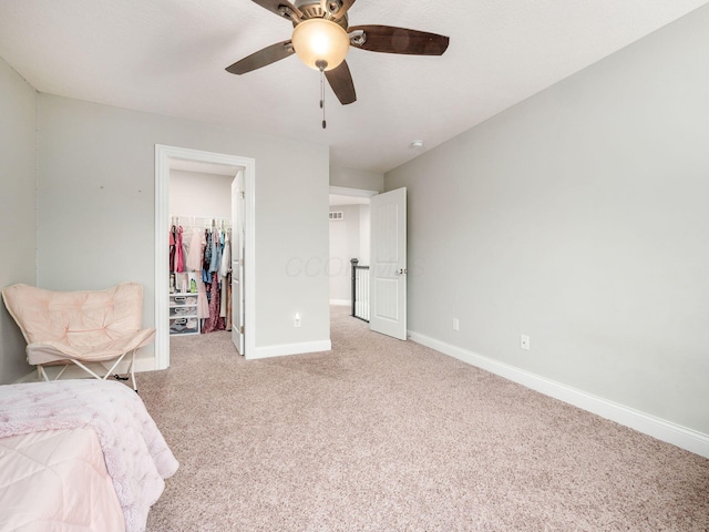 carpeted bedroom featuring a closet, a spacious closet, and ceiling fan