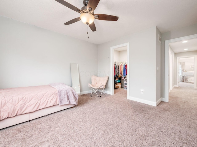 carpeted bedroom with a walk in closet, ceiling fan, and a closet