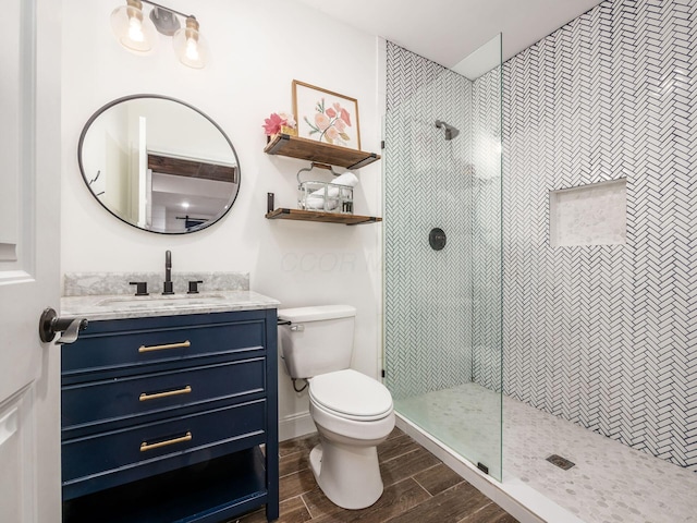 bathroom featuring a tile shower, vanity, and toilet