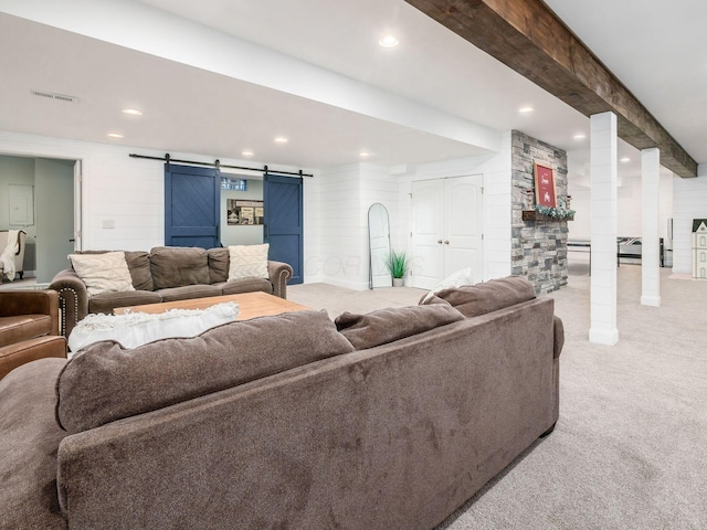 living room with beam ceiling, a barn door, and light colored carpet