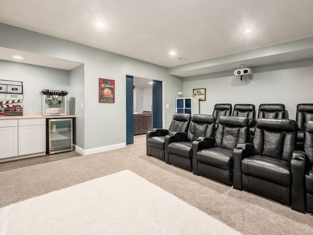 cinema room featuring wine cooler, light colored carpet, and bar