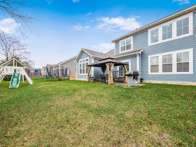 rear view of property with a playground, a gazebo, a trampoline, and a lawn