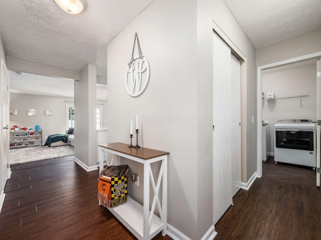 hall with separate washer and dryer, dark hardwood / wood-style flooring, and a textured ceiling