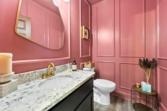 bathroom with wood-type flooring, vanity, and toilet