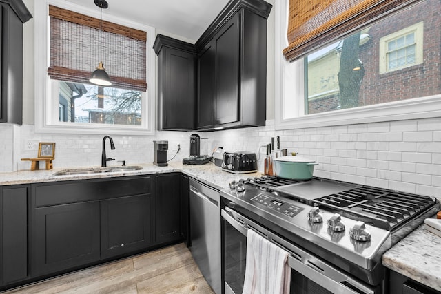 kitchen with backsplash, sink, pendant lighting, and appliances with stainless steel finishes