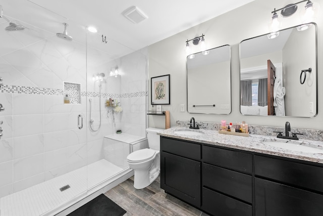 bathroom with hardwood / wood-style floors, vanity, a shower with door, and toilet