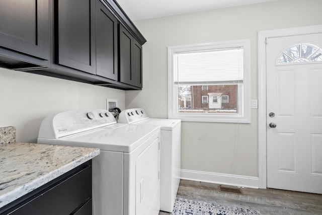 laundry room featuring washing machine and dryer, dark hardwood / wood-style flooring, and cabinets