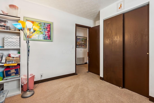 bedroom with light colored carpet, a textured ceiling, and a closet