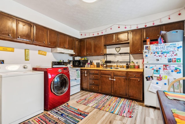 washroom featuring washer and clothes dryer, light hardwood / wood-style flooring, sink, and a textured ceiling