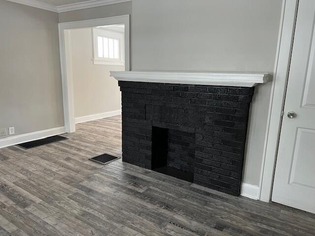 interior details featuring wood-type flooring, ornamental molding, and a fireplace