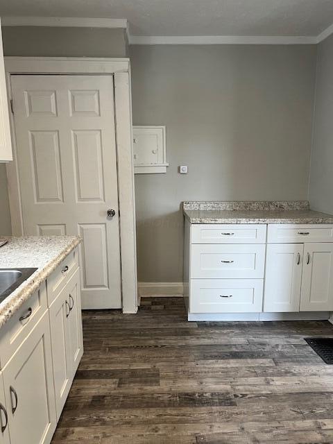 kitchen featuring white cabinets, light stone counters, and ornamental molding