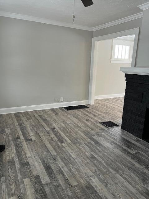 unfurnished living room featuring hardwood / wood-style floors, a brick fireplace, ceiling fan, and crown molding