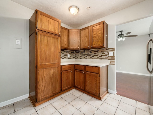 kitchen featuring a textured ceiling, ceiling fan, light tile patterned floors, and tasteful backsplash