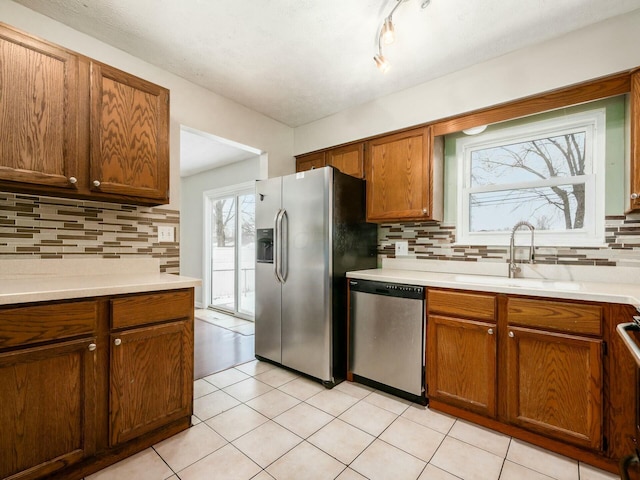 kitchen with sink, appliances with stainless steel finishes, light tile patterned floors, and decorative backsplash