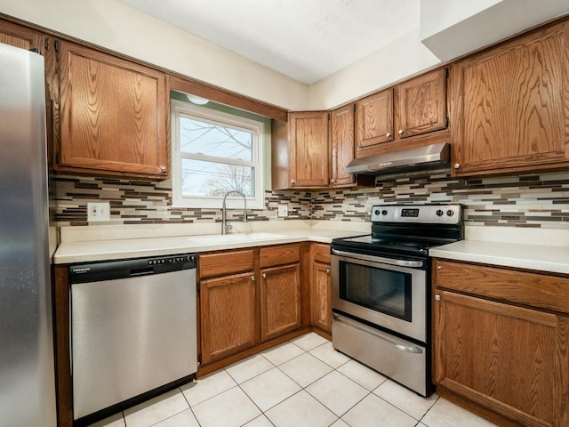 kitchen with sink, light tile patterned flooring, decorative backsplash, and appliances with stainless steel finishes