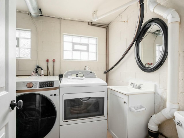 clothes washing area with washer and clothes dryer and sink