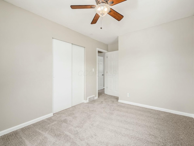 unfurnished bedroom featuring light colored carpet, ceiling fan, and a closet