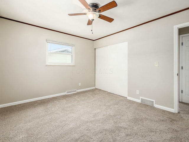 carpeted spare room with ceiling fan and ornamental molding