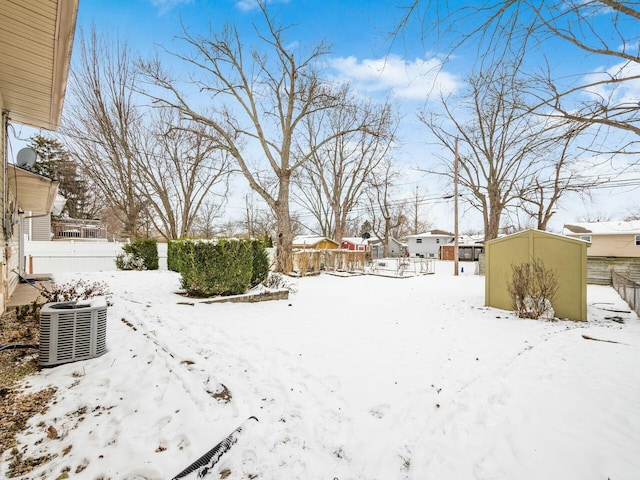 yard layered in snow with central air condition unit and a shed