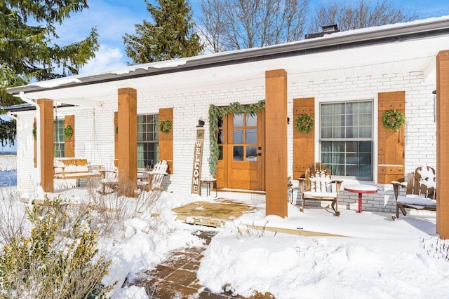 snow covered property entrance with covered porch