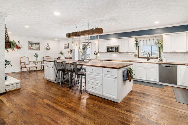 kitchen featuring a center island, white cabinets, stainless steel appliances, and decorative light fixtures