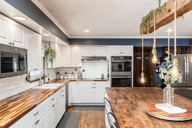 kitchen with wood counters, backsplash, white cabinets, and sink