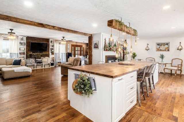 kitchen with white cabinets, a textured ceiling, a kitchen island, and butcher block counters