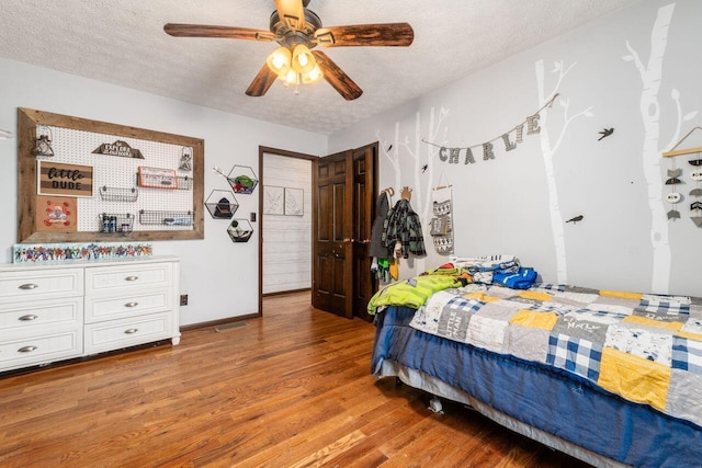 bedroom with hardwood / wood-style floors, ceiling fan, and a textured ceiling