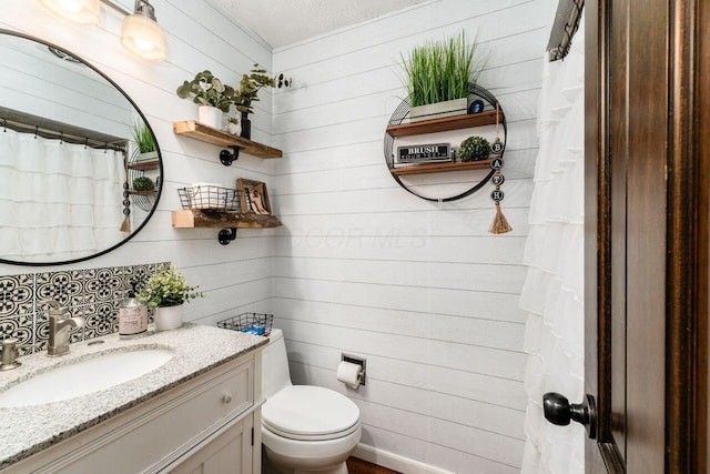 bathroom with vanity, a textured ceiling, toilet, and wood walls