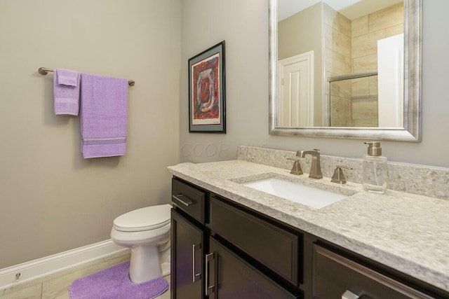 bathroom featuring a shower with door, vanity, and toilet