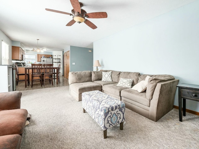 carpeted living room with ceiling fan with notable chandelier