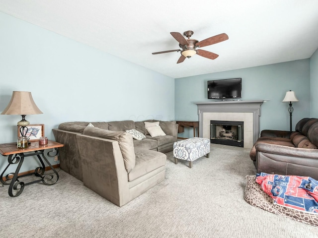 living room featuring a tile fireplace, ceiling fan, and carpet floors