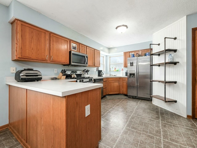 kitchen featuring kitchen peninsula, sink, a textured ceiling, and appliances with stainless steel finishes