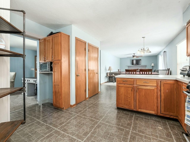 kitchen featuring pendant lighting, ceiling fan with notable chandelier, stove, and kitchen peninsula