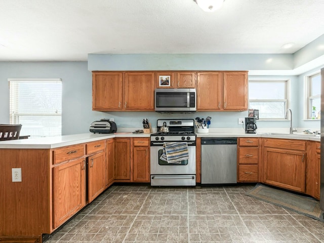 kitchen featuring kitchen peninsula, stainless steel appliances, a healthy amount of sunlight, and sink