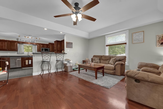 living room featuring light wood-type flooring, rail lighting, ceiling fan, and sink