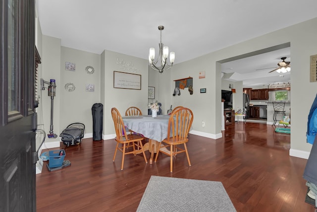 dining room with dark hardwood / wood-style flooring and ceiling fan with notable chandelier