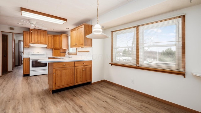 kitchen featuring white range, light hardwood / wood-style flooring, hanging light fixtures, and sink