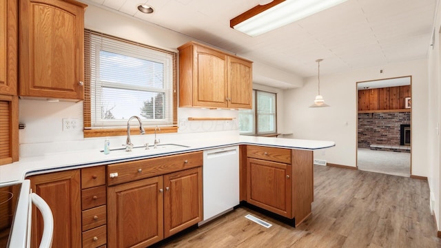 kitchen with dishwasher, stove, sink, decorative light fixtures, and kitchen peninsula